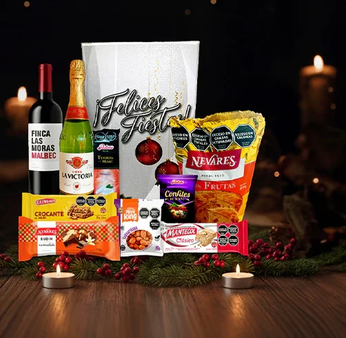 Caja navideña de Tu Caja de Navidad con vino, espumante, pan dulce y más, sobre una mesa con velas